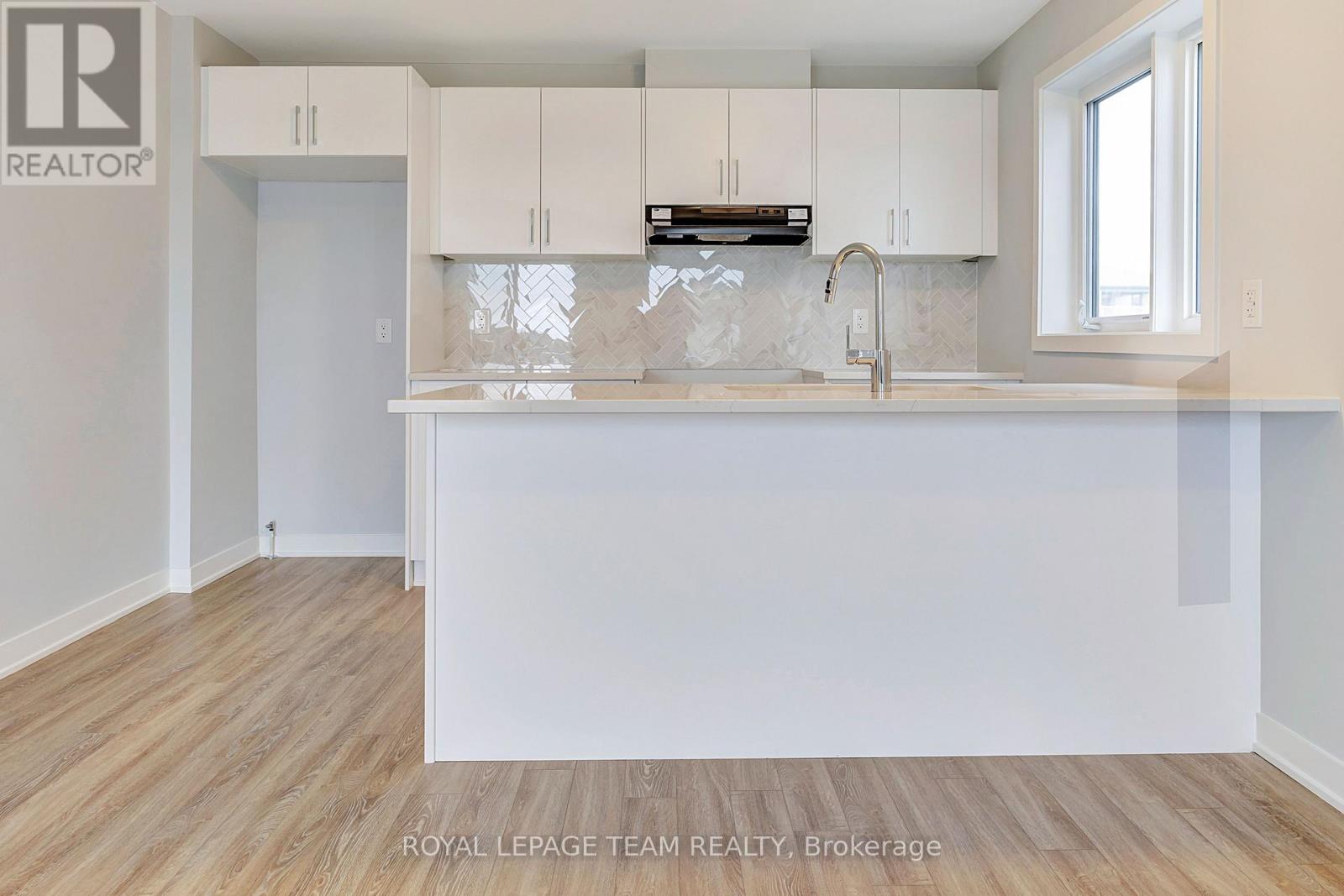 A kitchen with white cabinets and a wooden floor.