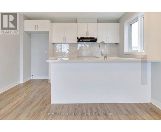 A kitchen with white cabinets and a wooden floor.