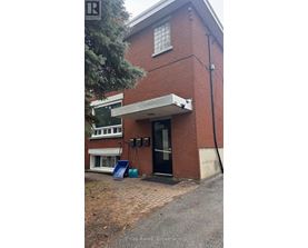 A red brick building with a black door and a small porch.