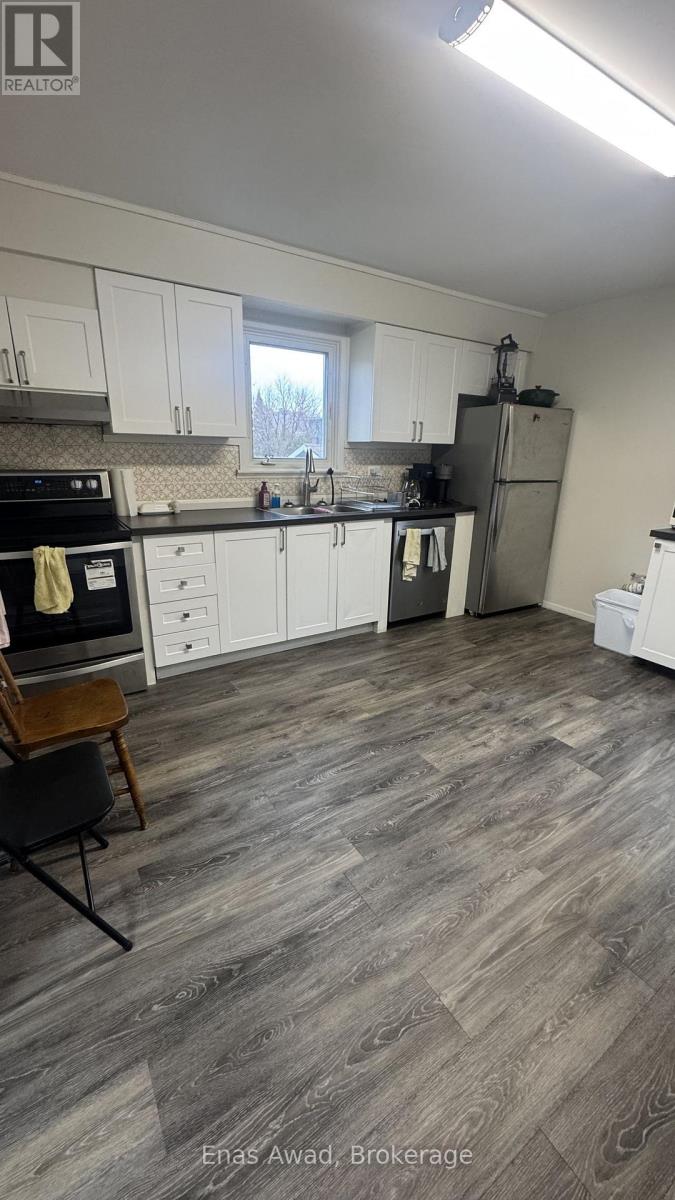 A kitchen with white cabinets and a wooden floor.