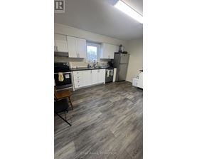 A kitchen with white cabinets and a wooden floor.