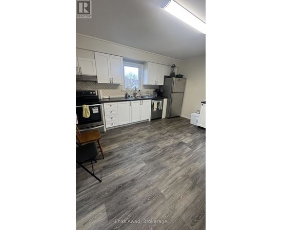 A kitchen with white cabinets and a wooden floor.
