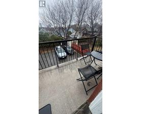 A balcony with a black chair and a table.