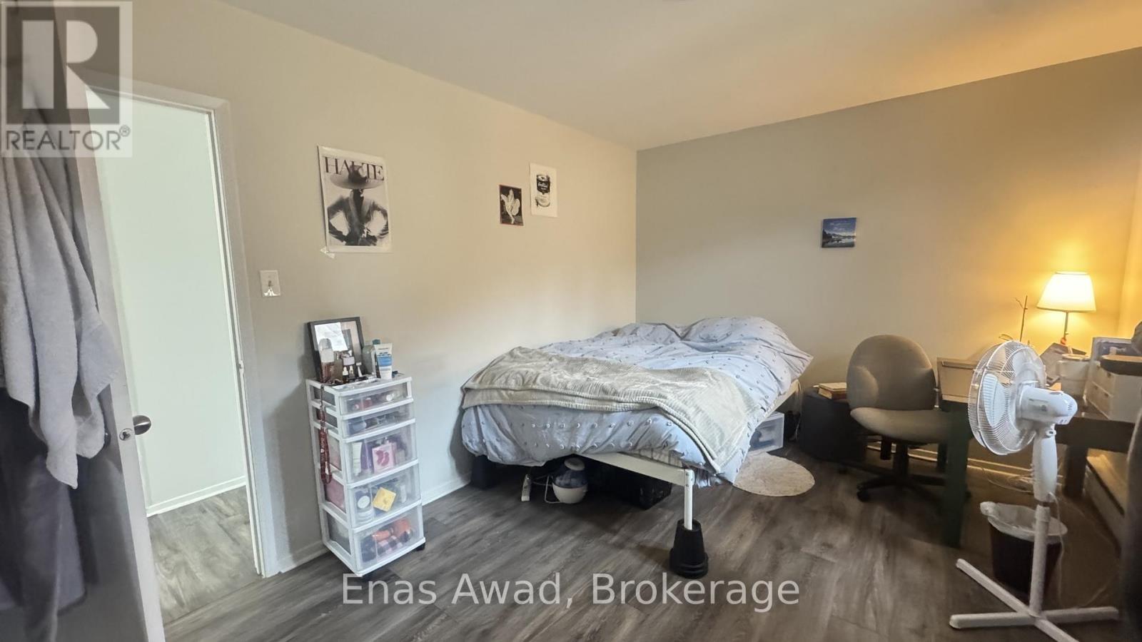 A bedroom with a bed, chair, and fan.