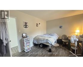 A bedroom with a bed, chair, and fan.