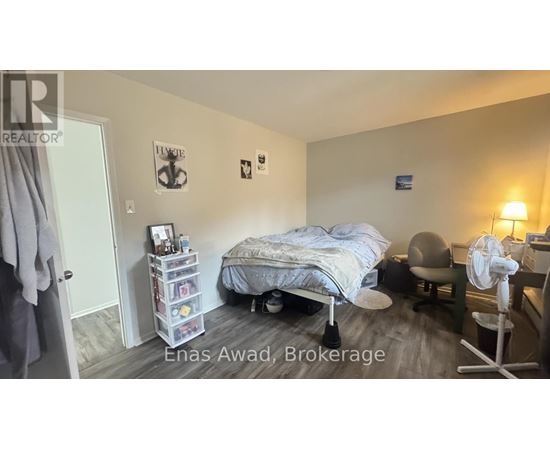 A bedroom with a bed, chair, and fan.