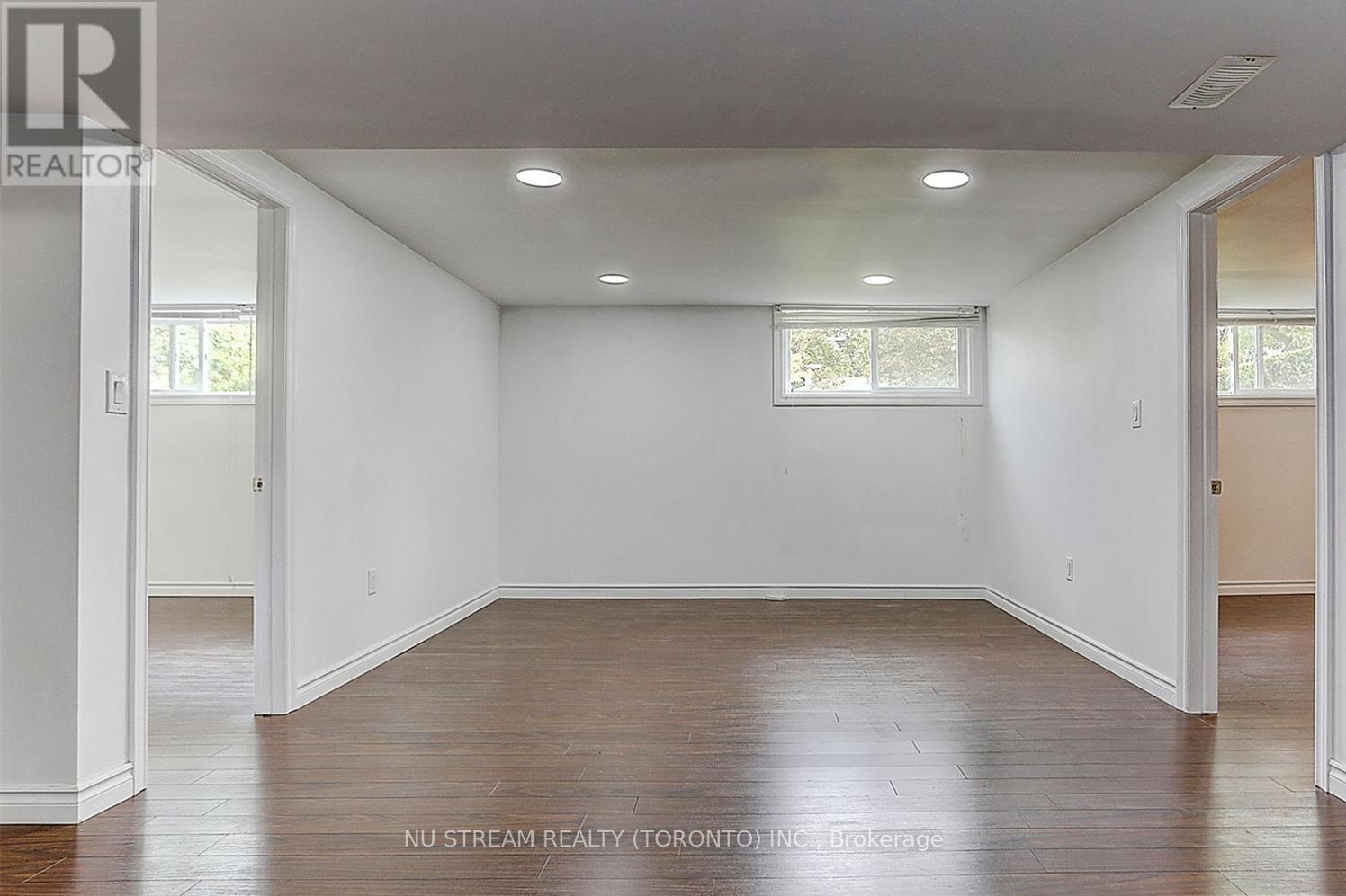 A spacious room with white walls and wooden flooring.
