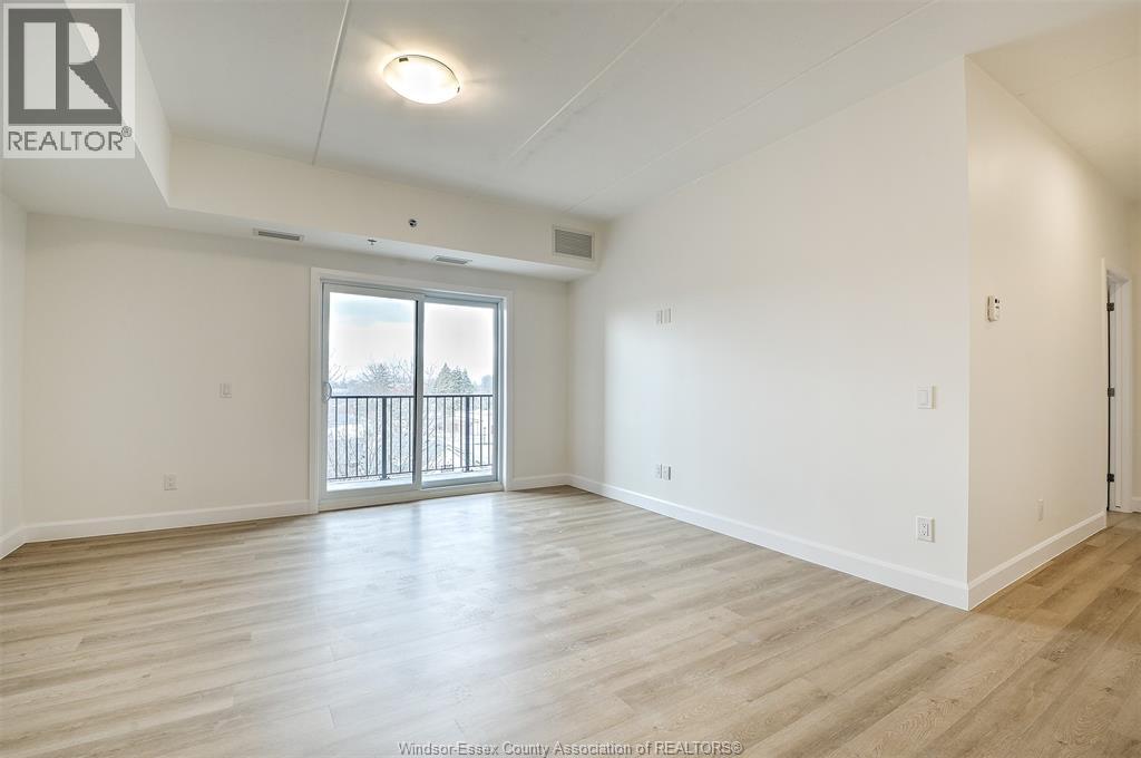 A spacious room with a sliding glass door and wooden flooring.