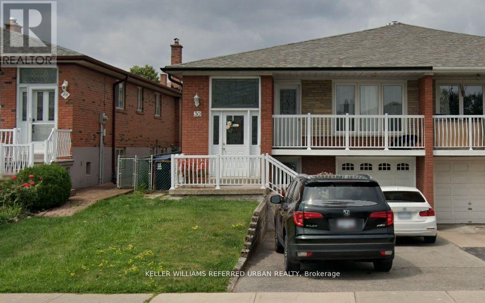 A black car is parked in front of a house with a white fence.