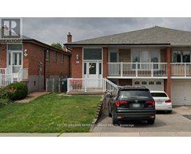 A black car is parked in front of a house with a white fence.