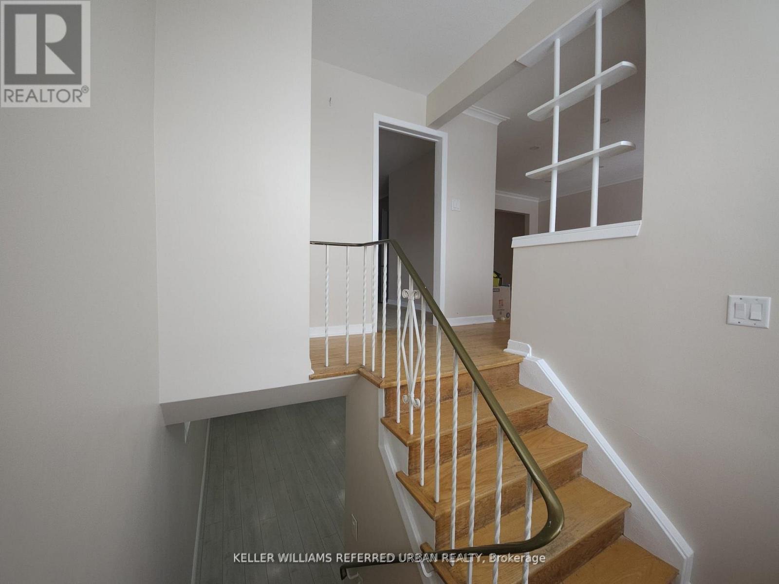 A staircase with a wooden handrail and a glass door at the bottom.