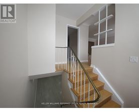 A staircase with a wooden handrail and a glass door at the bottom.