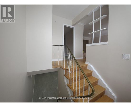 A staircase with a wooden handrail and a glass door at the bottom.