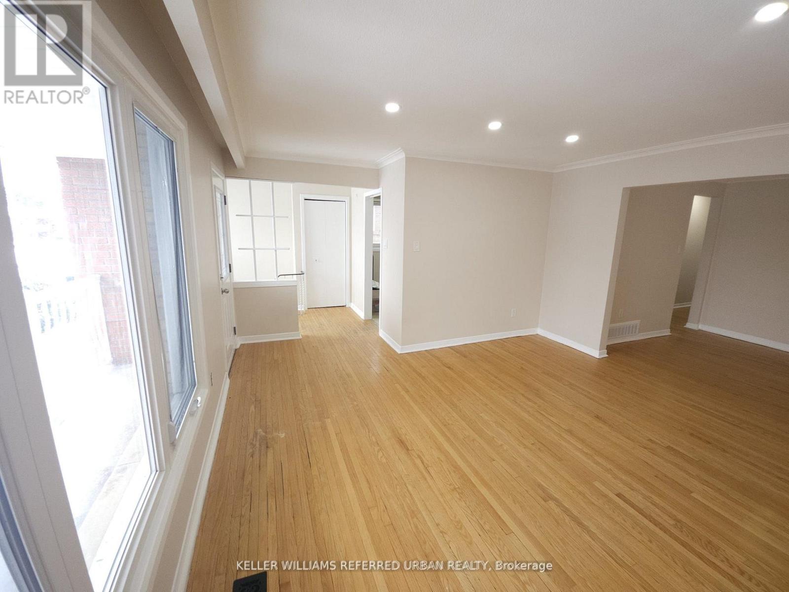 A spacious room with wooden flooring and white walls.