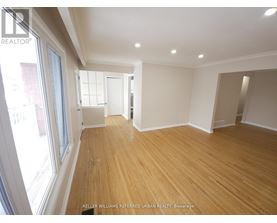 A spacious room with wooden flooring and white walls.