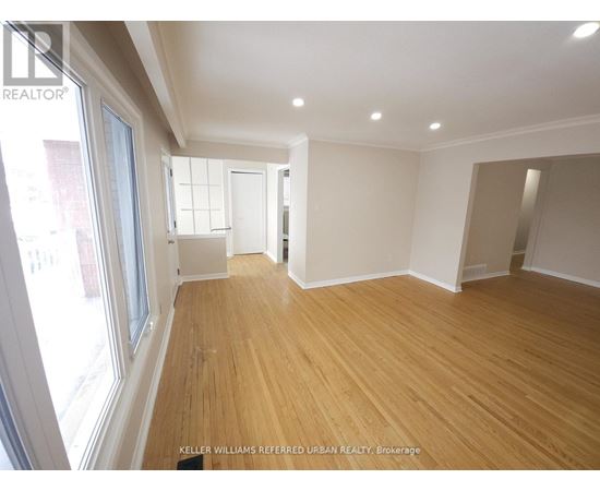 A spacious room with wooden flooring and white walls.