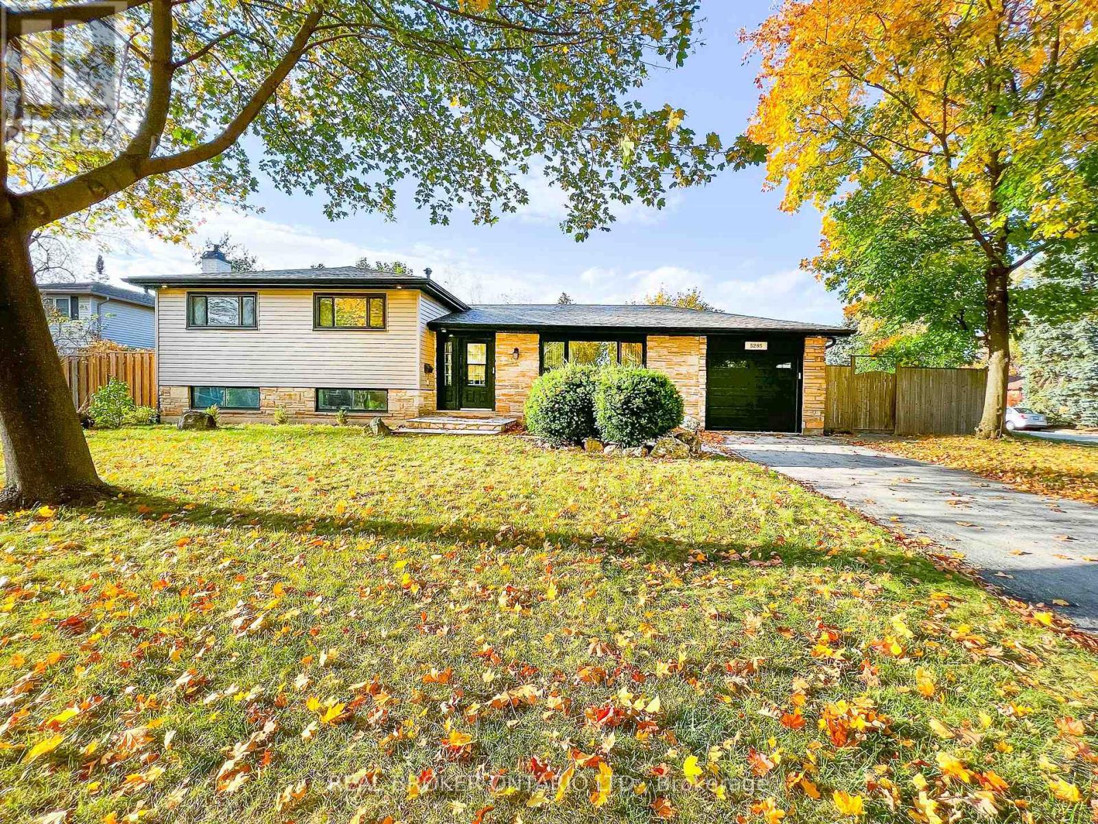A house with a green lawn and trees with yellow leaves.