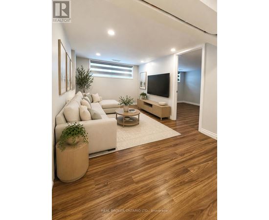 A living room with a white couch, a wooden floor, and a flat screen TV.