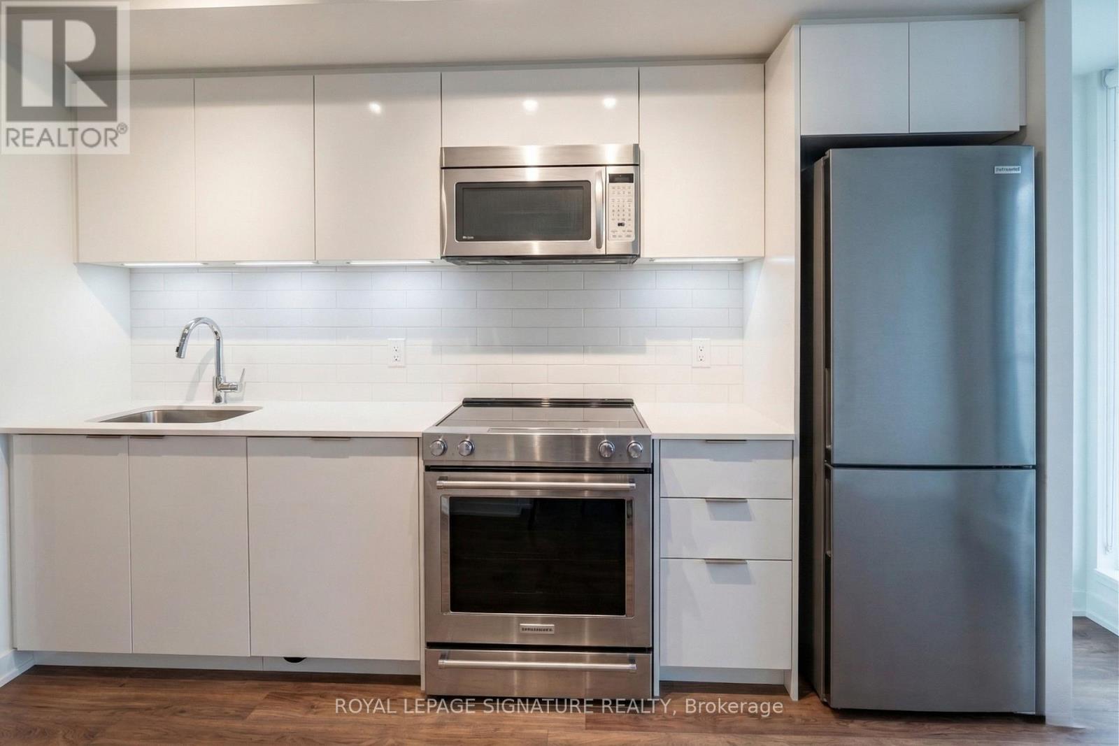 A modern kitchen with a stainless steel refrigerator and oven.