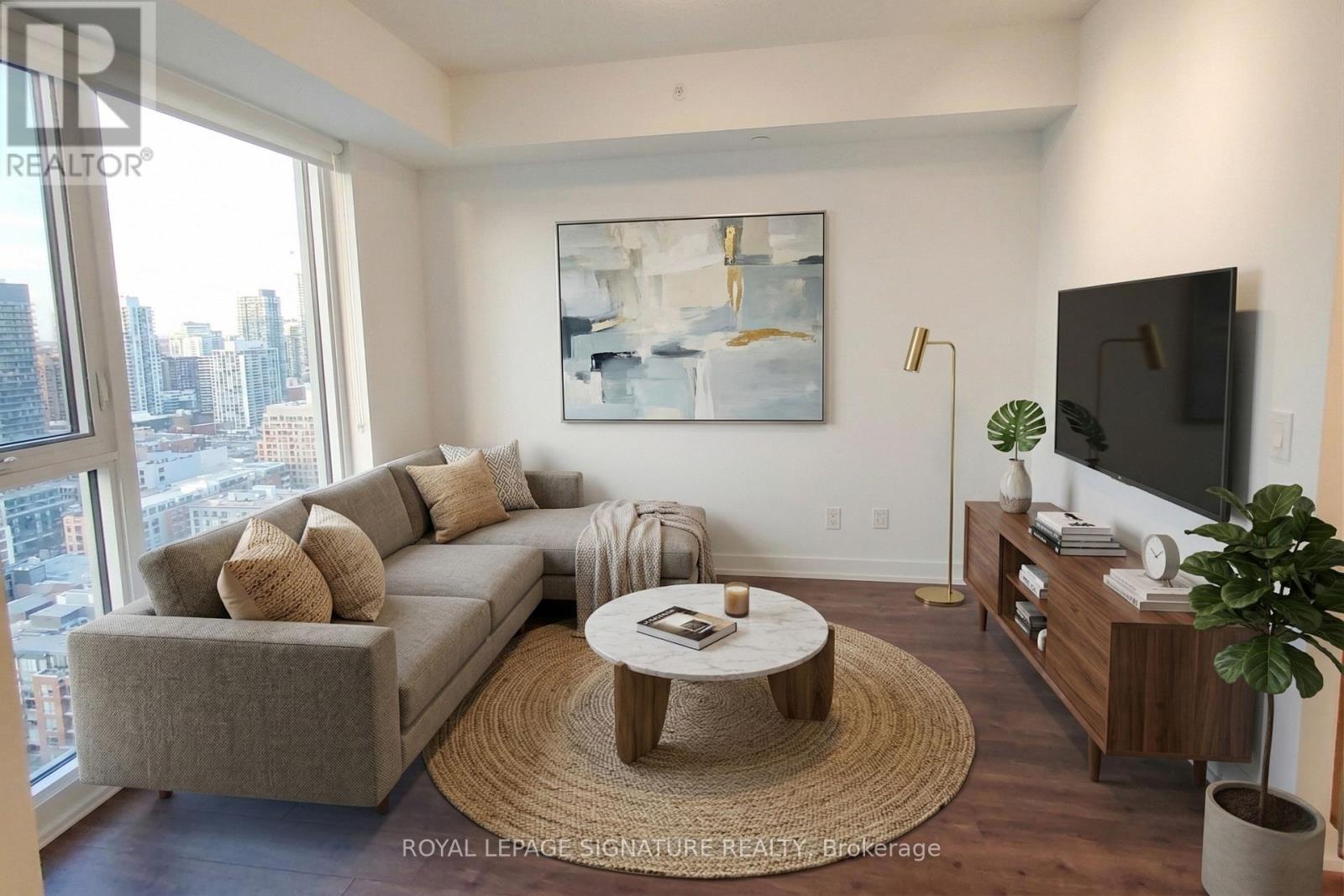 A living room with a grey couch, a coffee table, a television, and a painting on the wall.