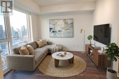 A living room with a grey couch, a coffee table, a television, and a painting on the wall.