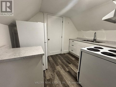 A kitchen with a white fridge, sink, and stove top oven.