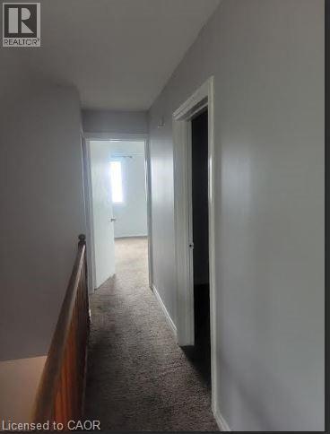 A hallway with a carpeted floor and white walls.