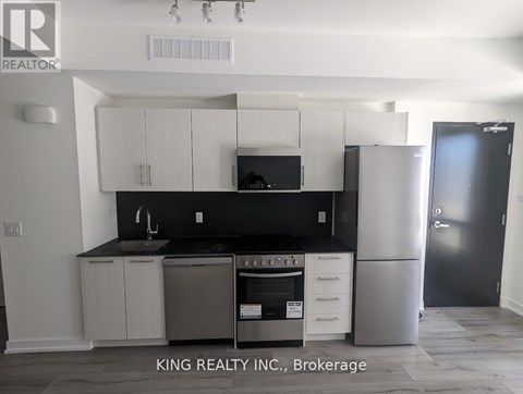 A kitchen with white cabinets and black countertops.