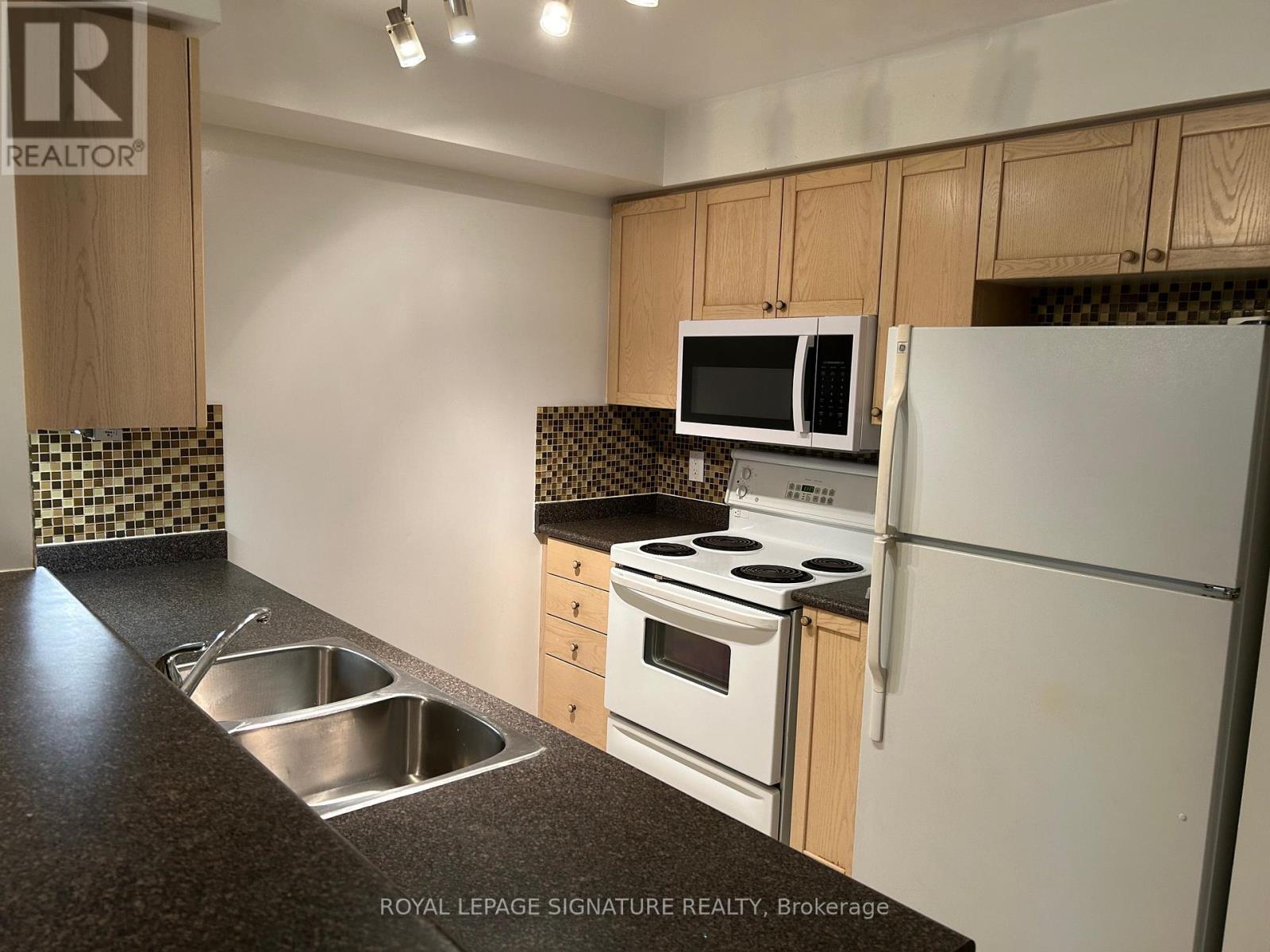 A kitchen with a sink, stove, and refrigerator.