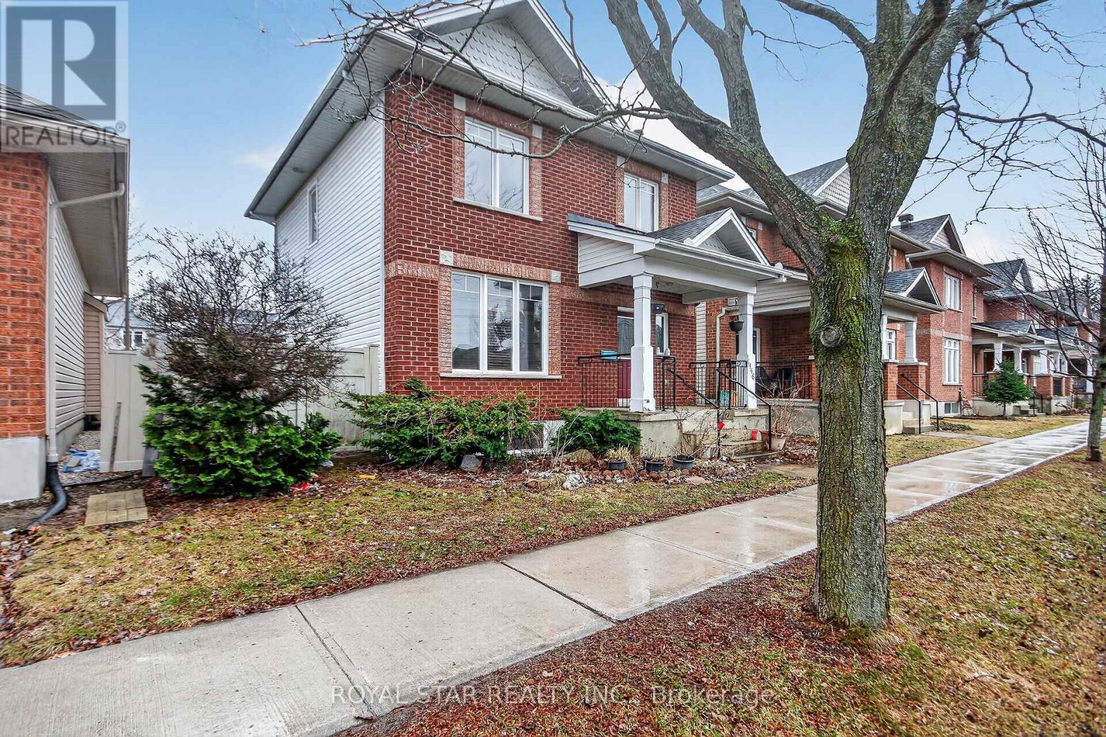 A red brick house with a white trim and a tree in front.