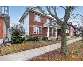 A red brick house with a white trim and a tree in front.
