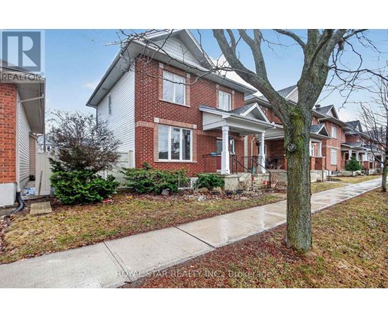 A red brick house with a white trim and a tree in front.