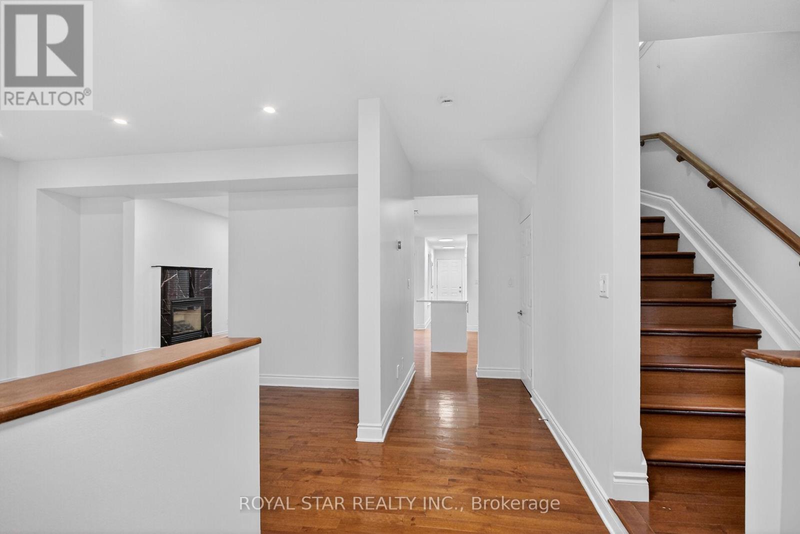 A spacious hallway with a staircase on the right and a fireplace on the left.