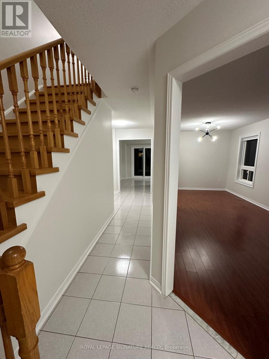 A hallway with a wooden staircase on the left and a white door on the right.