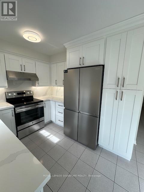 A kitchen with white cabinets and a stainless steel refrigerator.