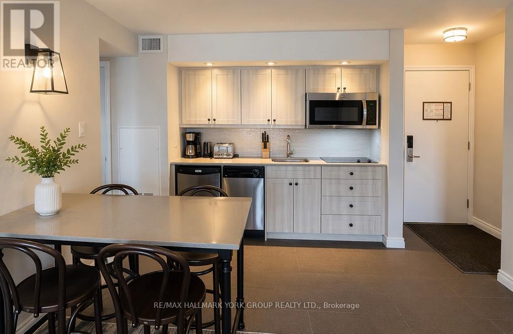 A kitchen with a table and chairs in the foreground and a microwave above the counter.