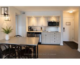 A kitchen with a table and chairs in the foreground and a microwave above the counter.