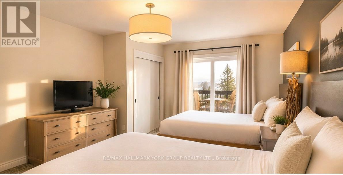 A bedroom with a large bed, a television, and a window with a view of trees.
