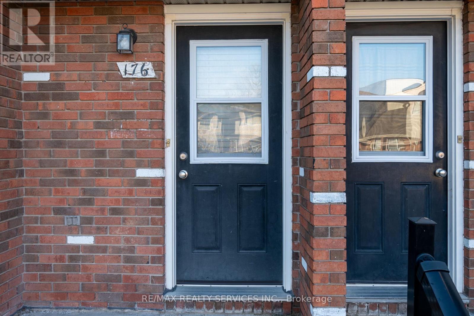 A black door with a glass window is on a brick wall.