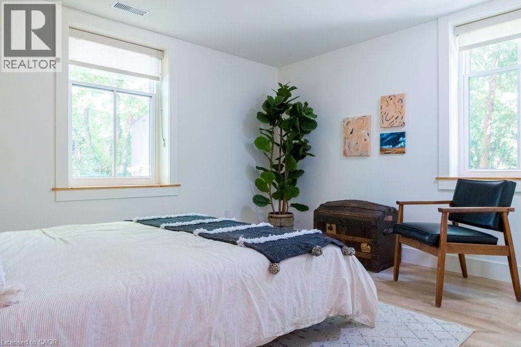A bedroom with a bed, chair, and a plant.