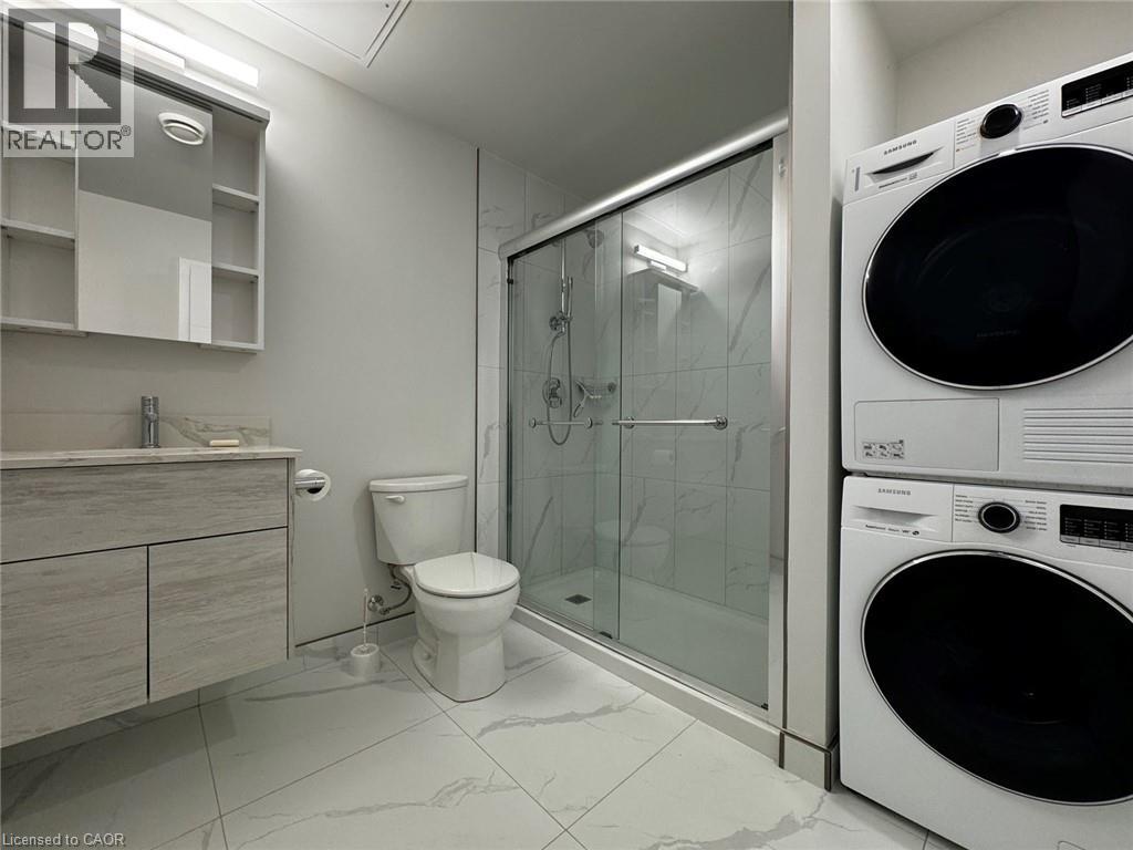 A white washing machine sits next to a glass shower stall in a modern bathroom.