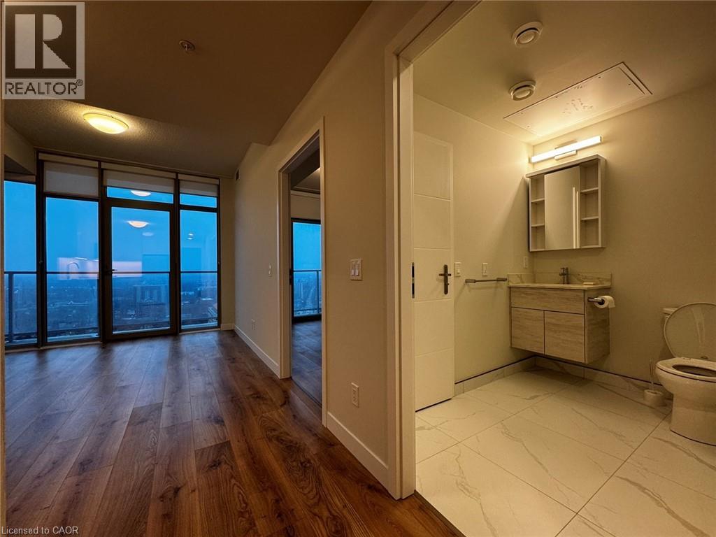 A bathroom with a toilet, sink, and a view of the city.