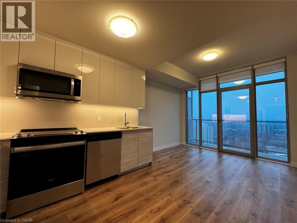 A well-lit kitchen with wooden floors and a view of the city through the sliding glass doors.