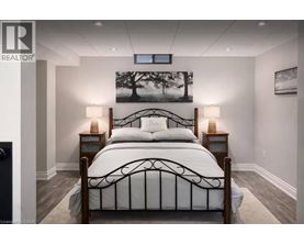 A bedroom with a large bed and a painting of a tree on the wall.
