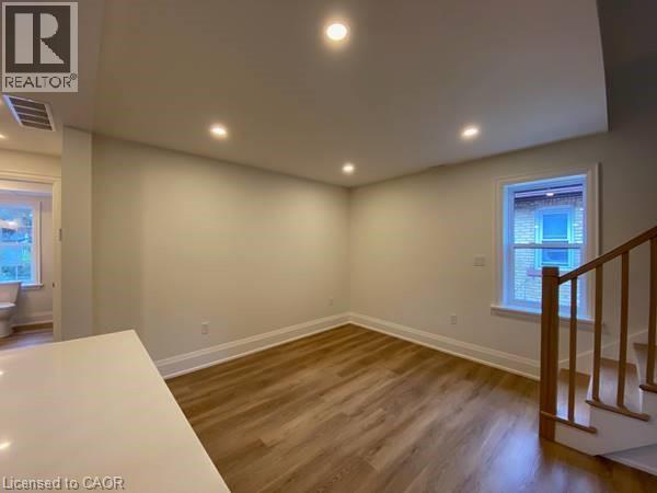 A room with wooden floors and a window with a view of buildings outside.
