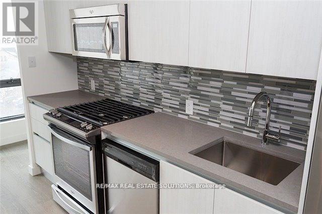 A modern kitchen with a stove, microwave, and a sink.