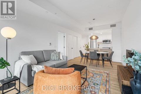 A modern living room with a grey sofa, a grey armchair, a black coffee table, a wooden dining table with chairs, a rug, and a potted plant.