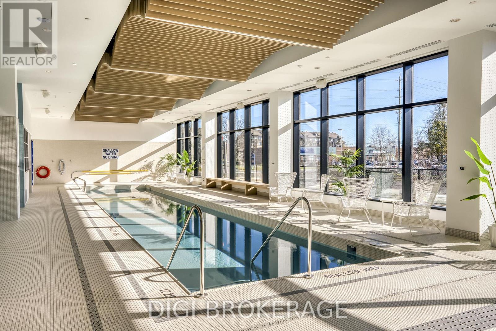 A large indoor swimming pool with a wooden ceiling and a view of the outdoors through the windows.