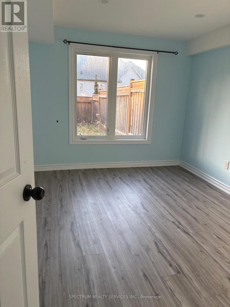 A room with light blue walls and wood flooring with a window and a door.