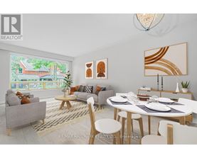 A modern dining room with a white table and chairs, a grey sofa, and a large window with a view of a house.